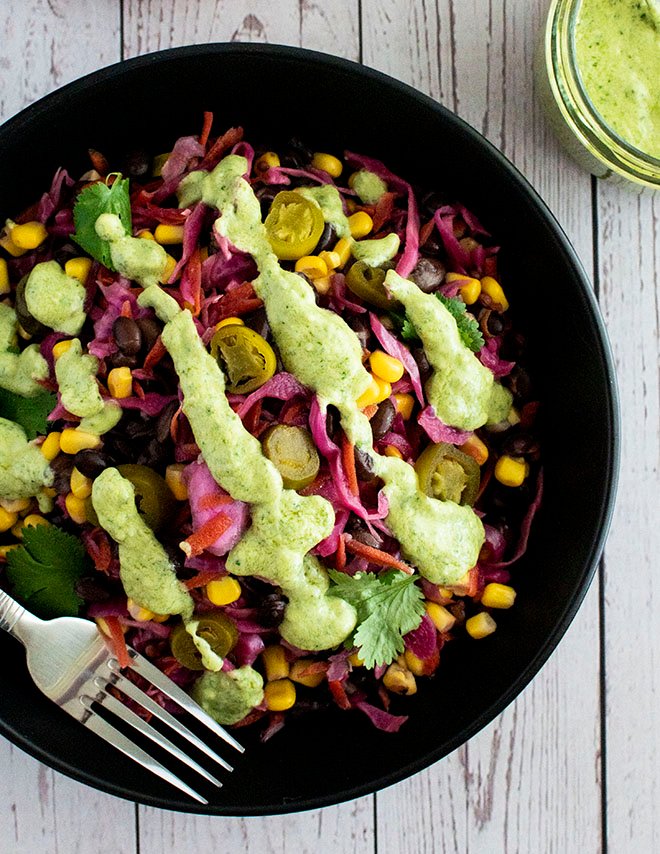 An overhead shot of Mexican pickled slaw drizzled with avocado, jalapeno and lime crema.