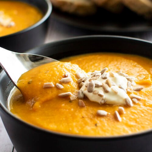A spoonful of pumpkin, sundried tomato and lentil soup being lifted out of a bowl.