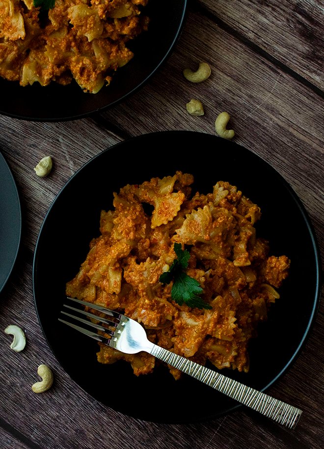 An overhead shot of 2 bowls of roast pepper and cashew pesto pasta.