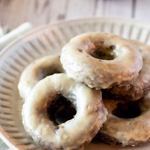 A bunch of lemon doughnuts with white chocolate glaze stacked on a plate.