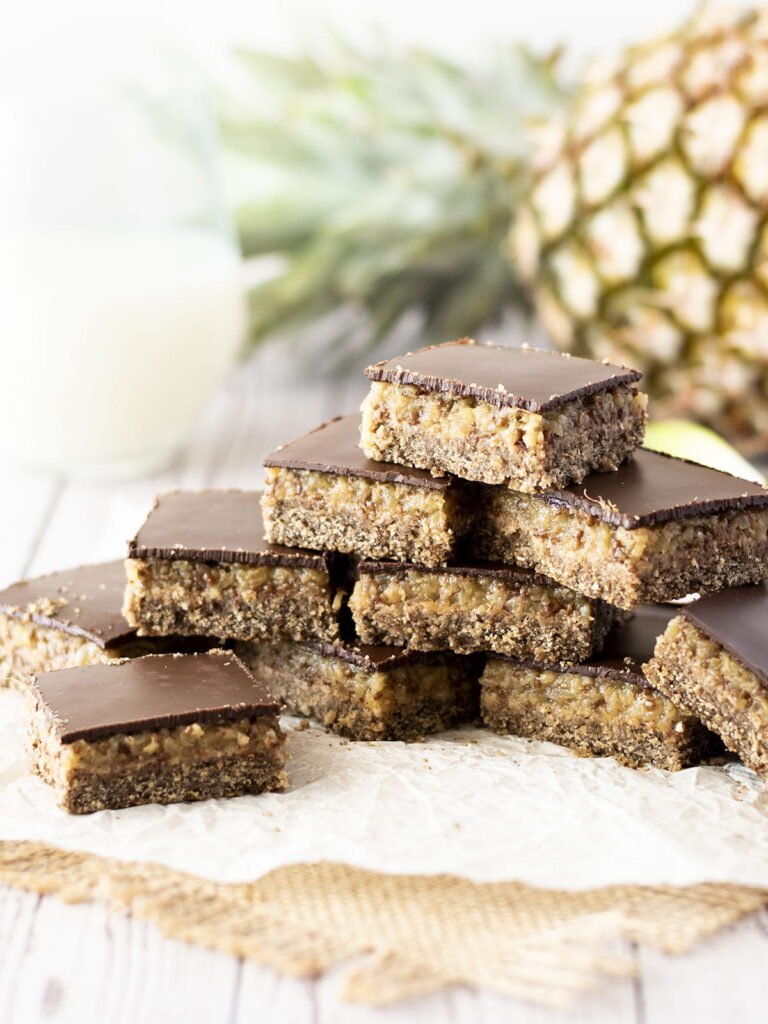 Nine stacked pieces of Caribbean spiced pineapple slice on baking paper.