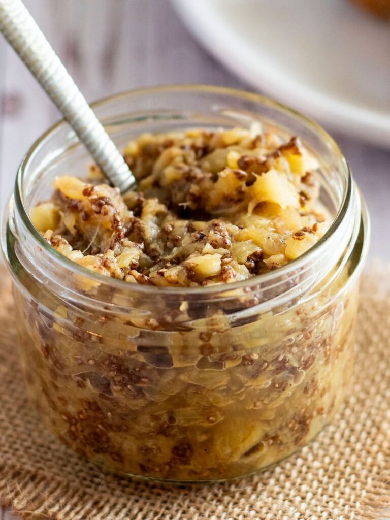 A jar of spiced pinepple jam with a spoon.