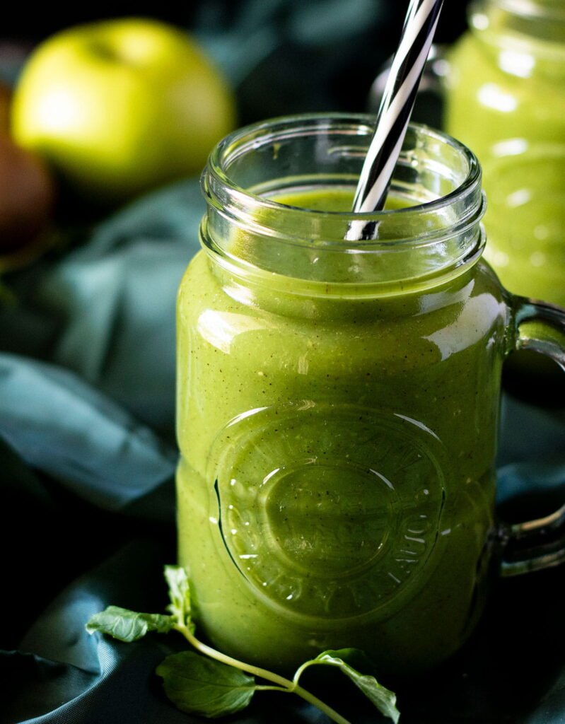 A mason jar full of fresh kiwi juice with a straw.