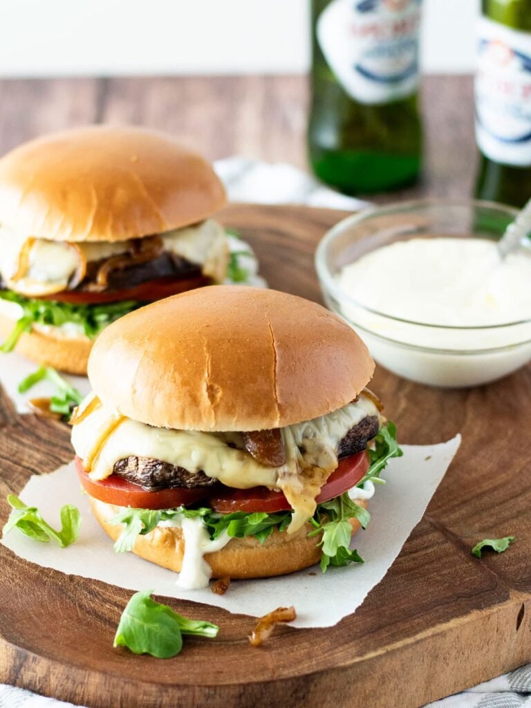 Two portobello mushroom burgers with a bowl of yoghurt truffle sauce.