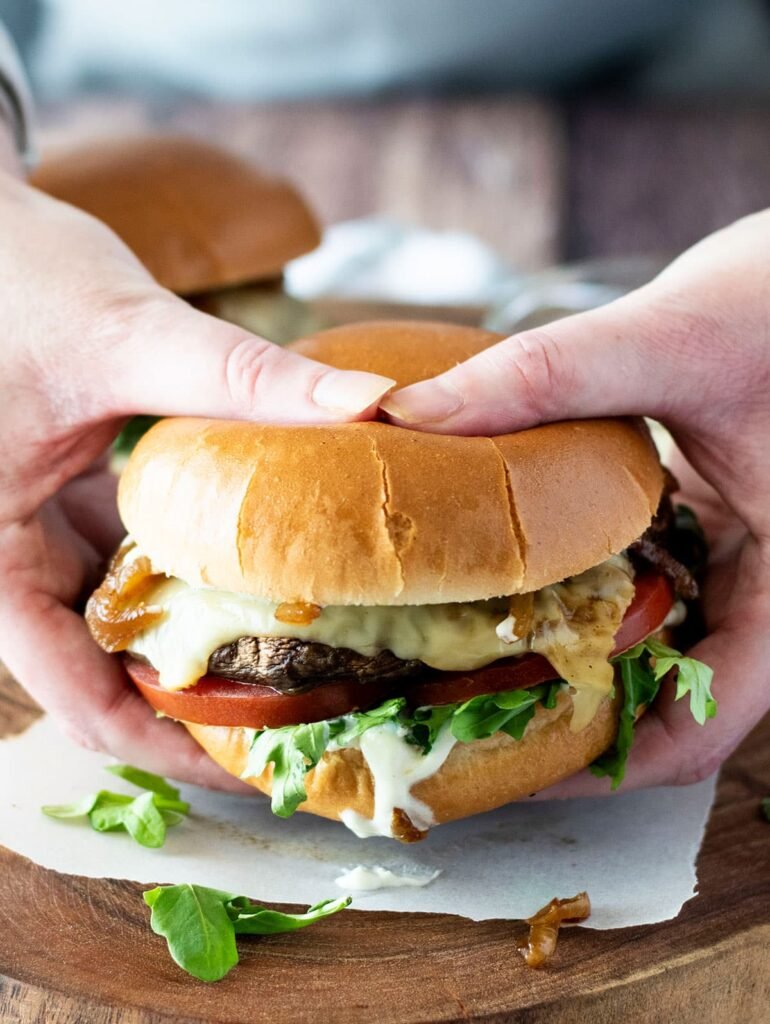 A portobello mushroom burger being held by two hands.