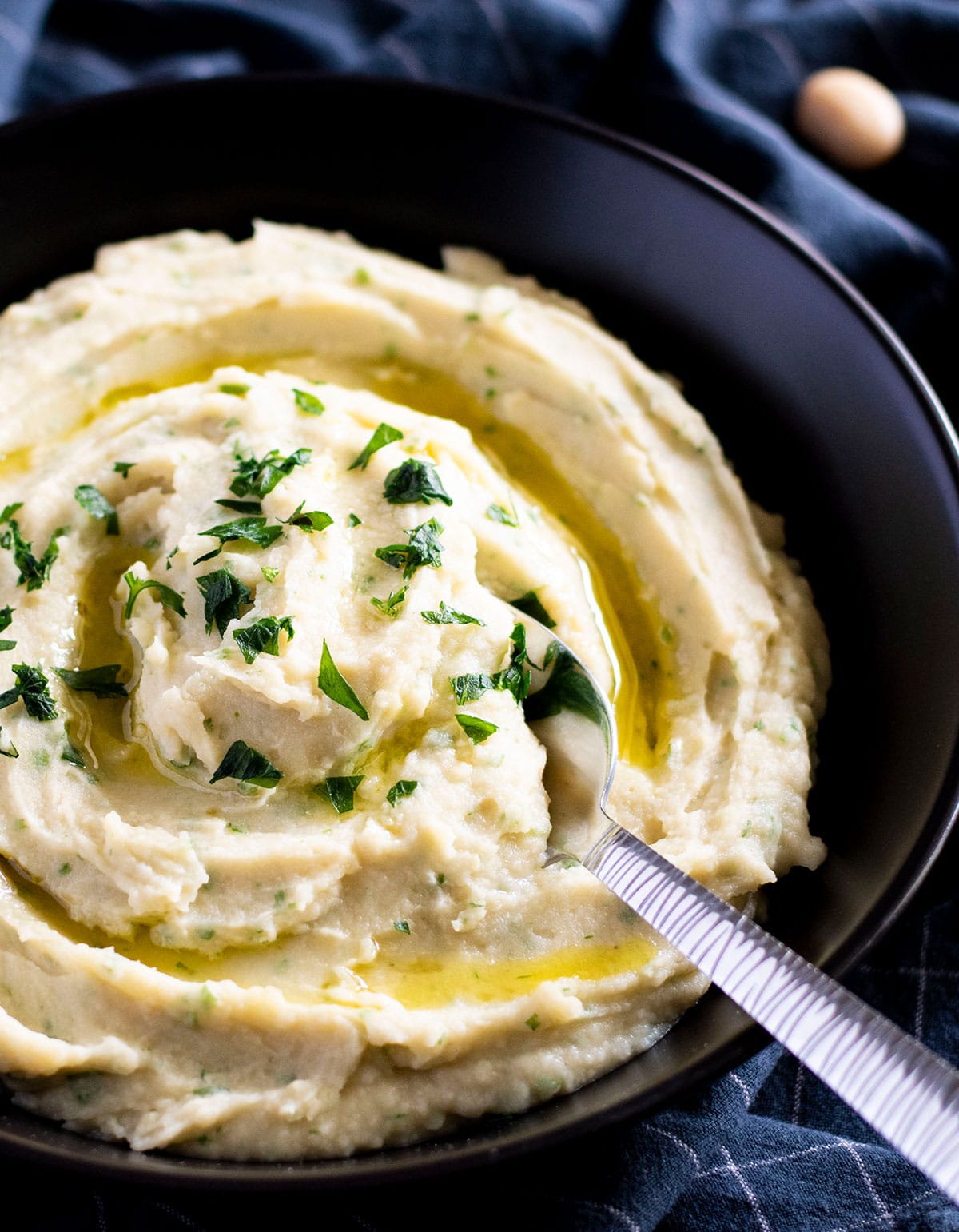 A bowl of potato and white bean mash with a spoon.