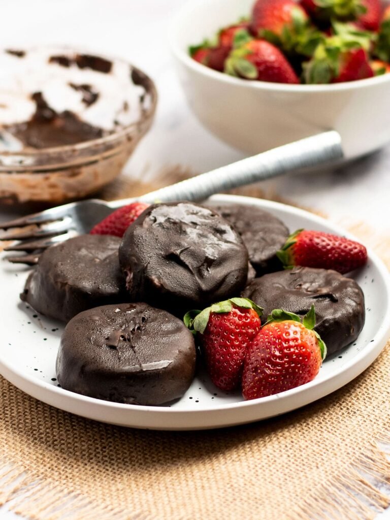 Five frozen strawberry and Greek yogurt bites on a plate with strawberries,