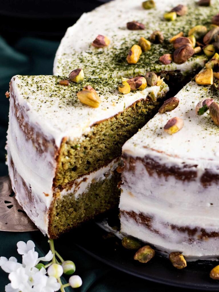 A slice being taken out of a pistachio and matcha cake.