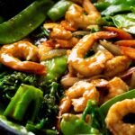 A skillet full of curry prawns stir fry.