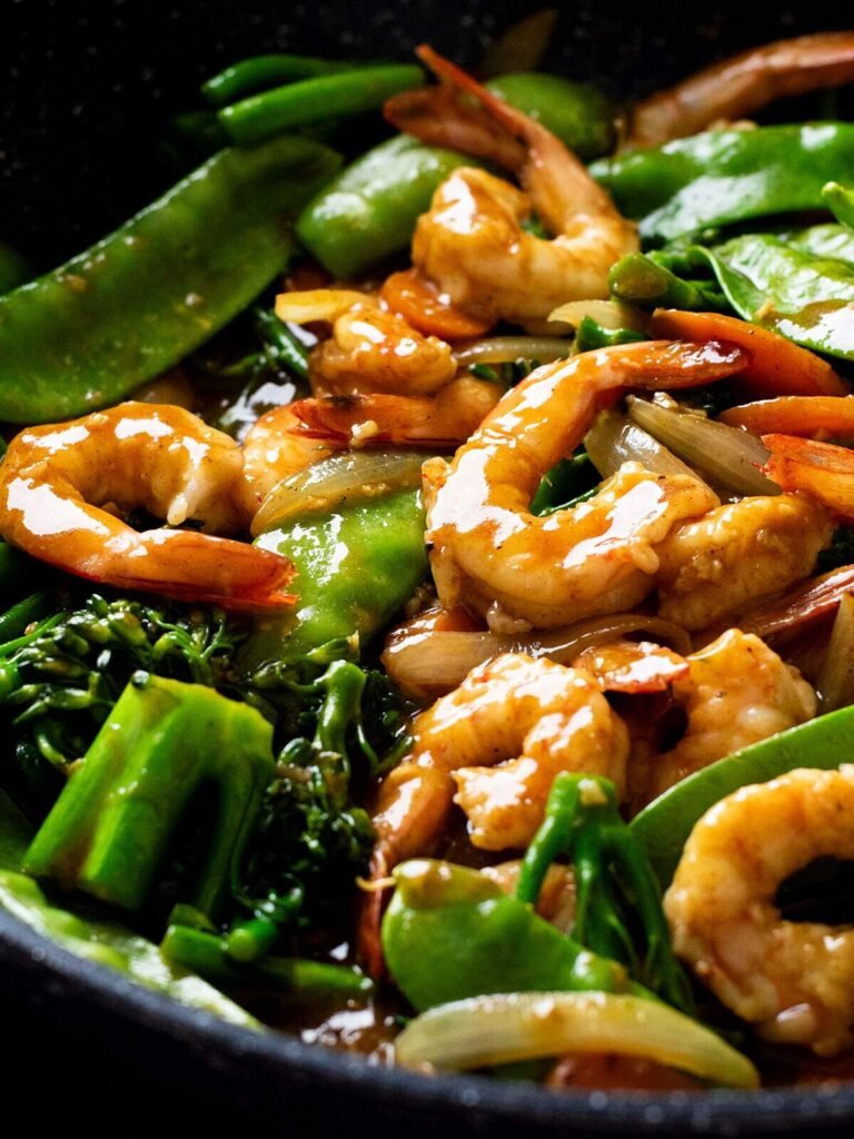 A skillet full of curry prawns stir fry.