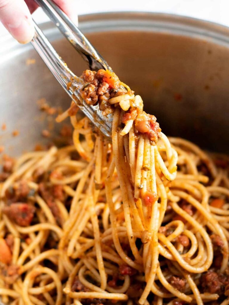 Tongues grabbing Beef and Lentil Bolognese with pasta.
