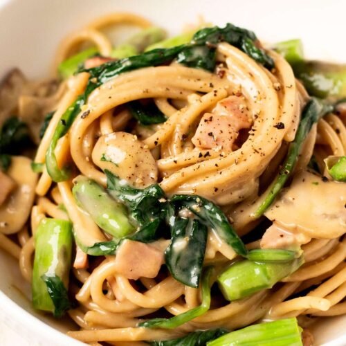 A bowl of healthy vegetable carbonara with asparagus and spinach.