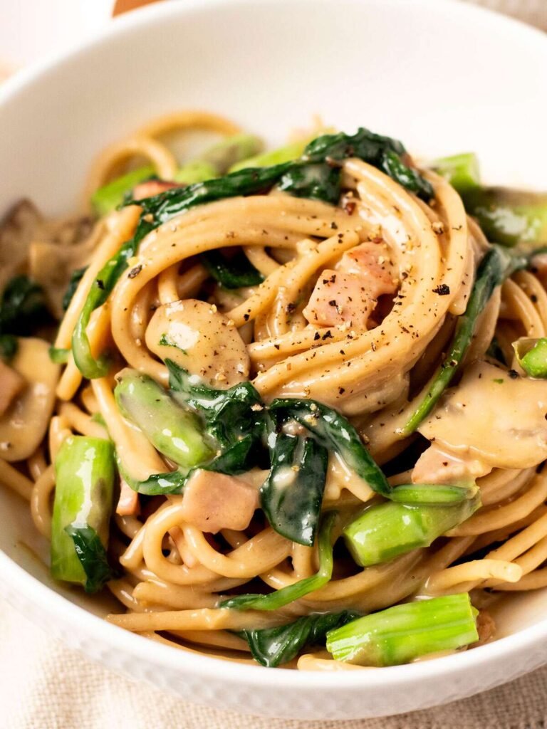 A bowl of healthy vegetable carbonara with asparagus and spinach.